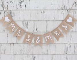 Mrs. & Mrs. on burlap pennants in simple white script with hearts at beginning and end