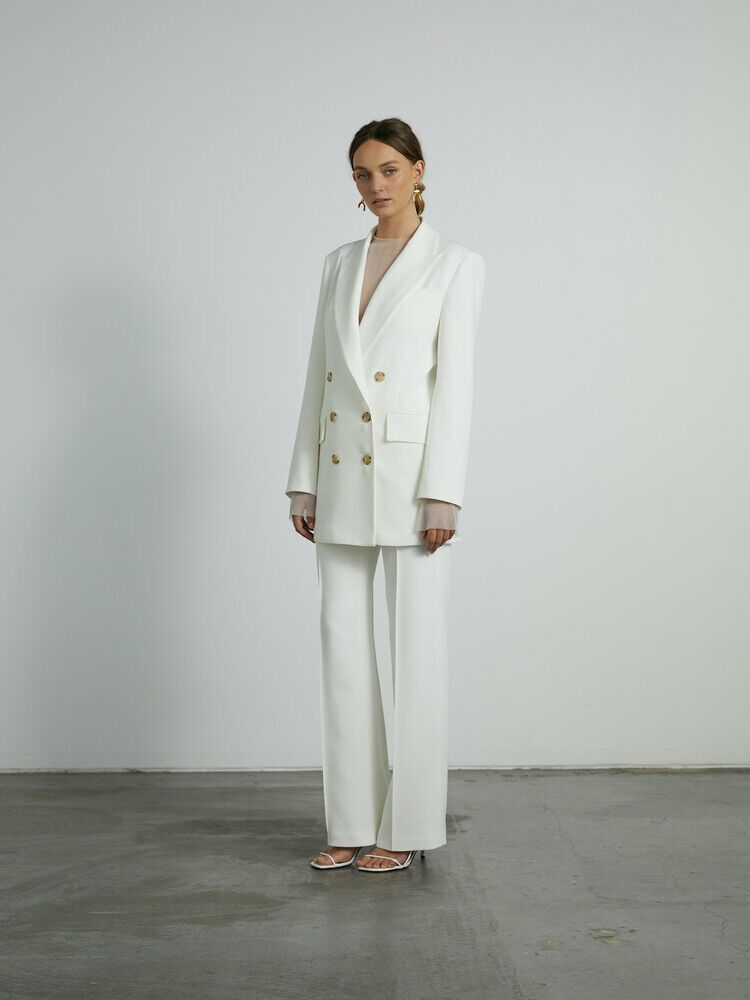 Model wears a chic white pantsuit with an oversized fit. 