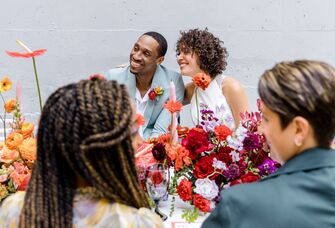 A couple lean in together, smiling, at this outdoor rehearsal dinner.