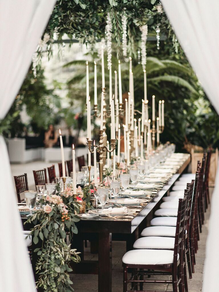 long dark wood wedding table with white taper candles in brass candelabras