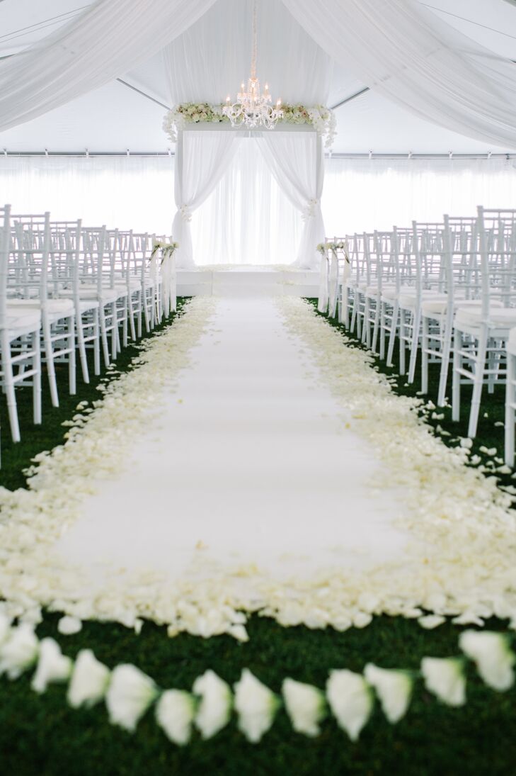 The couple exchanged vows under a white linen tent that was lined with ethereal curtains. Blakeney and Jake decked out their romantic ceremony site with a white fabric aisle runner lined with ivory rose petals, a chandelier, lush flowers and an arbor draped in sheer fabric.