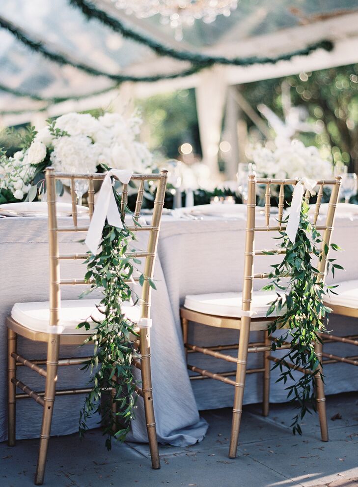 The couple’s head table was situated in a U shape of king’s tables with full, low arrangements and greenery running down the middle. “I liked the idea of mixing textures and chose crinkly gray tablecloths for all the tables under the tent,” Nina says. Down the back of the newlyweds' chairs, whimsical flowing fresh greenery ran down to the floor creating, a regal garden aesthetic.