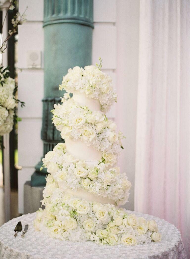 Ornate wedding cake covered in lots of fresh flowers