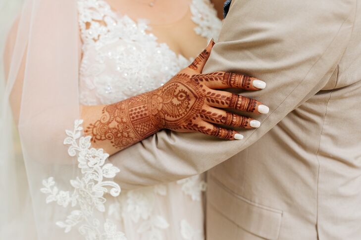Bride in Wedding Dress and Henna Hand With Groom in Tan Suit