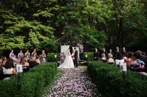 A Romantic Wedding Ceremony Filled With Rose Petals and Greenery Under an Iron Altar