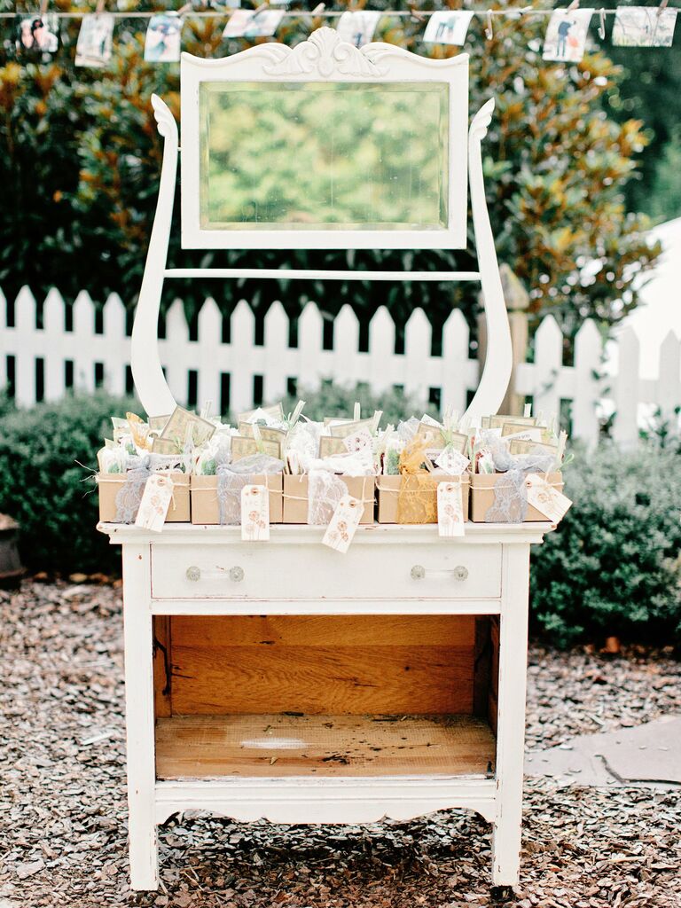 wedding favor display with boxes on top of white vintage vanity with mirror