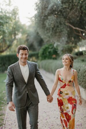 Bride in Red Rehearsal Dinner Dress and Groom in Gray Suit Holding Handing