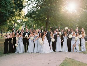 Wedding Party in Pale Blue and Black Smiles While Bride and Groom Kiss