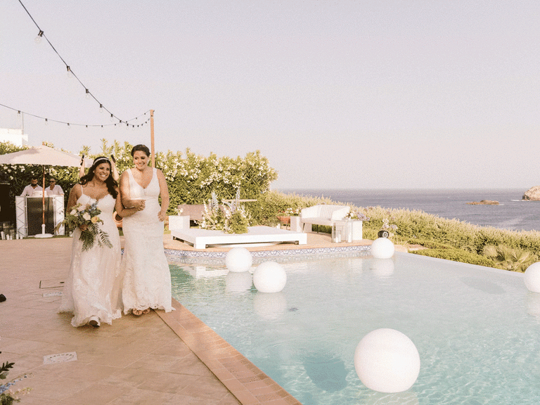 Brides walking along pool at wedding venue in Portugal.