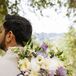 Colorful White and Lavender Bridal Bouquet Held Behind Groom