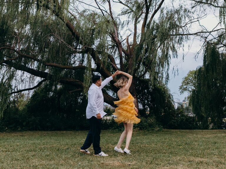 Two newly-engaged people twirl each other for their photoshoot