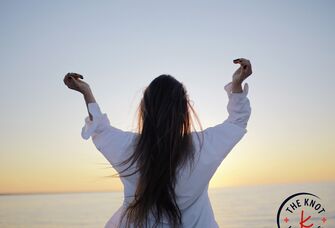 woman standing alone with arms up outside