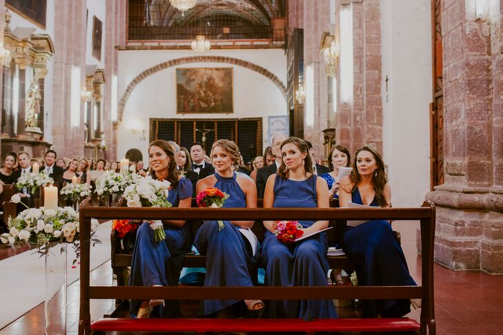 Taking the decor and setting into consideration, Marian had her bridesmaids choose long, formal Joanna August gowns in a rich shade of blue for their walk down the aisle. “This color was chosen so the flower color palette and the color of San Miguel would stand out without clashing with their dresses,” Marian says. Her bridesmaids chose their own styles, showing off all their personalities.