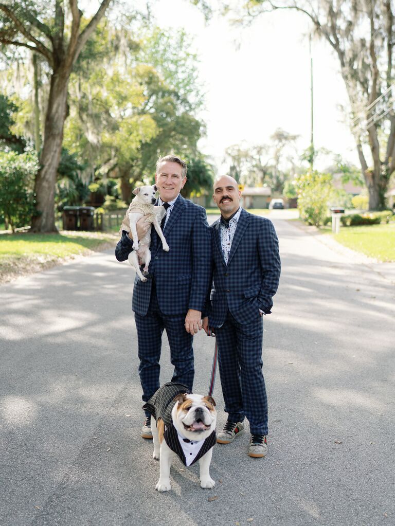 Grooms in matching suits and posing with their dogs.