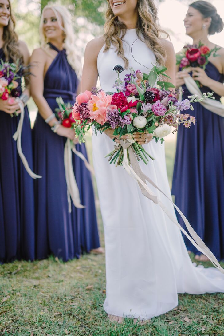 Madelyn carried an overflowing bouquet of organic blooms, incorporating hues of rich purple and pink. Her asymmetrical arrangement included peonies, garden roses, ranunculus, stock and wildflowers, hand-tied with a cascading ivory ribbon that swept the ground.