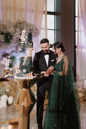 Bride in Emerald Green Lengha Dress and Groom in Classic Tuxedo Cut Their Green, Four-Tier Wedding Cake, Luxurious Dessert, Sikh Wedding Reception