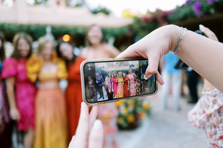 Guest Taking a Photo of Guests Dressed in Vibrant Colors With Smart Phone