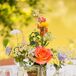 Small arrangements of wildflowers were displayed in glass bottles, giving the centerpiece decor a unique, natural touch.