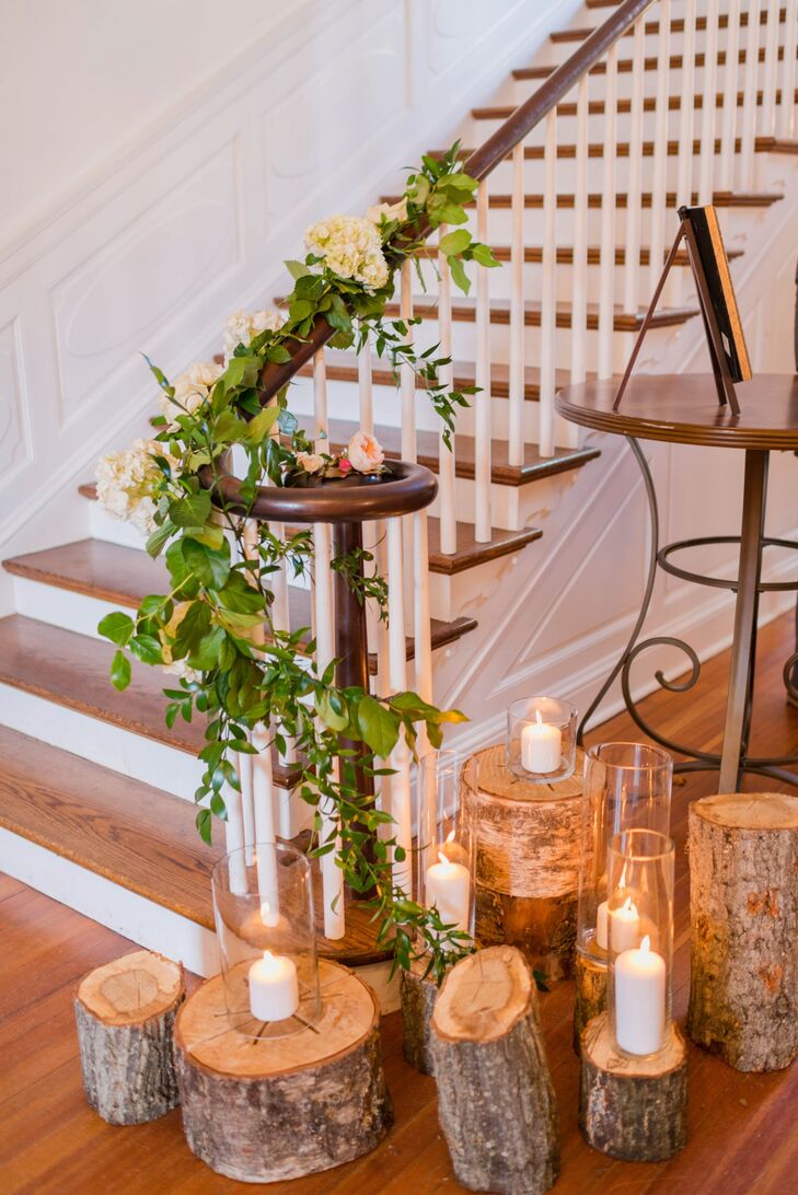 Rows of wooden logs with candles on top stood next to the staircase near the entrance of Rust Manor House in Leesburg, Virginia, adding a rustic touch to the wedding decor.