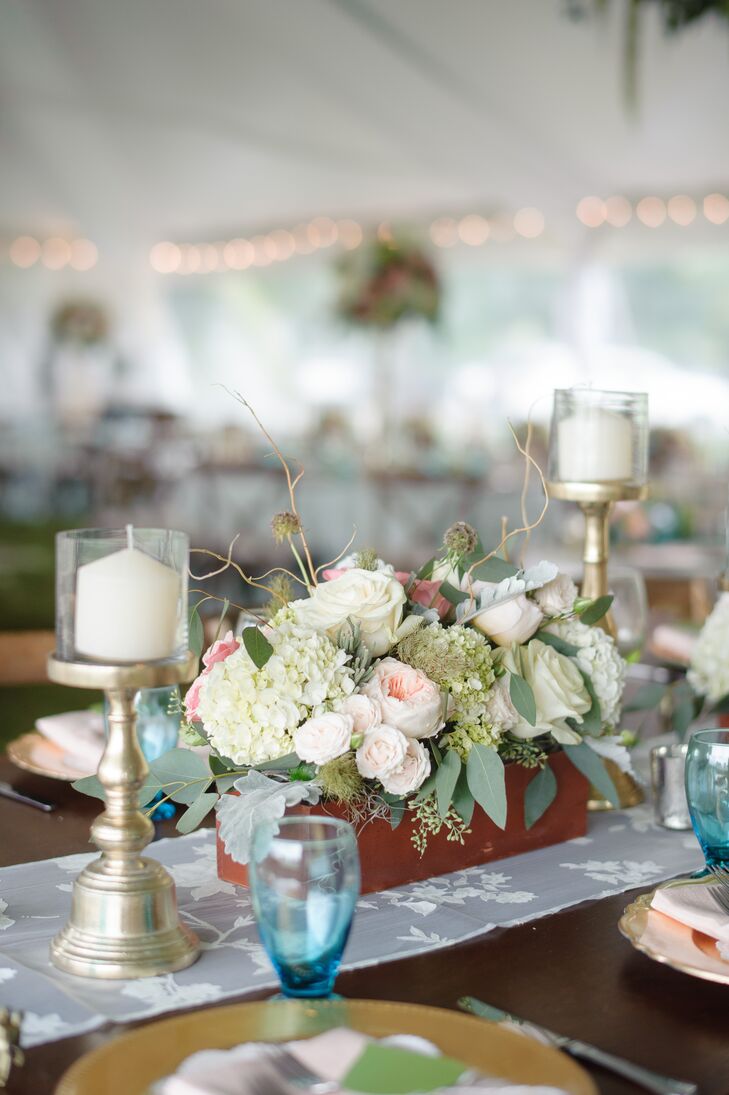 Some family style table had a wooden centerpiece filled with white and green hydrangeas, blush garden roses, white roses and scabiosa pods. Gold candlesticks surrounded the romantic floral decor on each end.