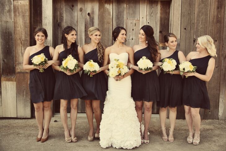 Bridesmaids wore knee-length one-shoulder navy dresses with their bouquets of yellow and white flowers.