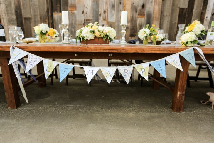 The head table was decorated with vintage candles and china, wooden planters, romantic floral arrangements and a pennant flag sign that spelled out, "Just married!"