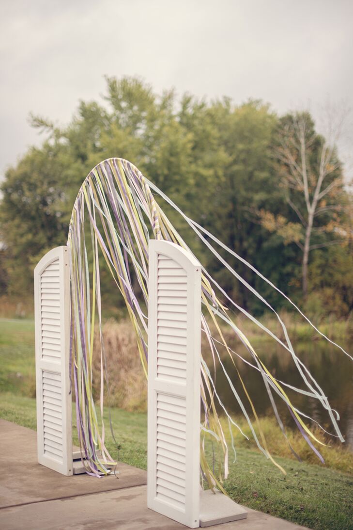 Now this is a new way to use window shutters! Erin and Cory's wedding arch was accented with twin white shutters. Colorful streamers decorated its  thin, wire frame.
