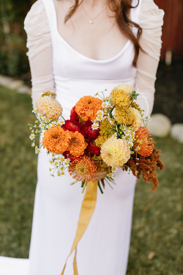 Bride Holding Bright, Desert-Inspired Bouquet of Red, Yellow and Burnt Orange Flowers