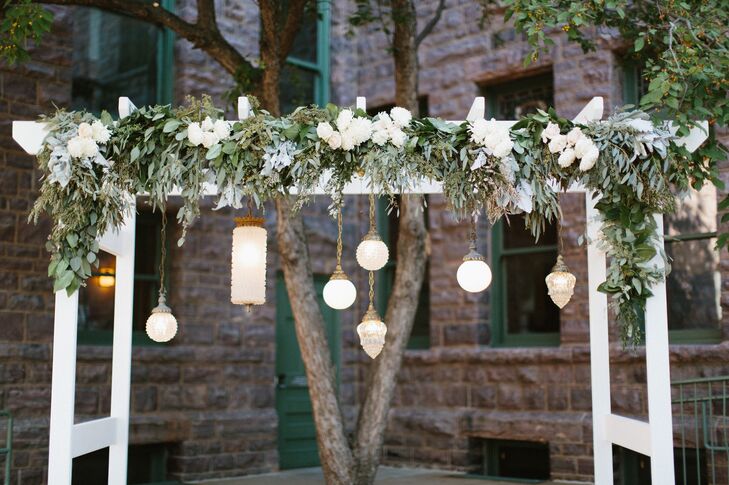 Dan and his father built the white wooden arbor under which the couple were married. It was draped in lush greens and ivory florals. Vintage glass lamps hung from the top offering a soft glow during the outdoor ceremony.