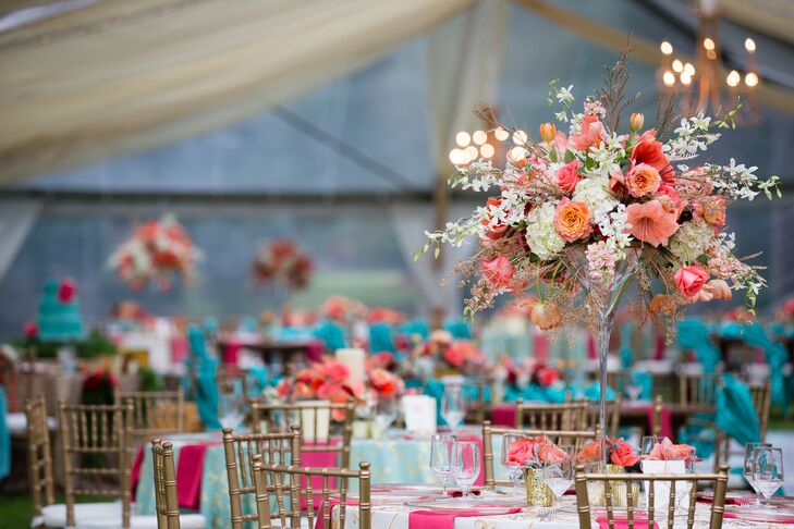 The round tables at the reception were topped with oversize martini glass vases filled with pink hibiscus, roses, white orchids and white hydrangeas for an overgrown garden feel. Madeline and Joe paired tall and low centerpieces to add dimension to the clear-tented reception.