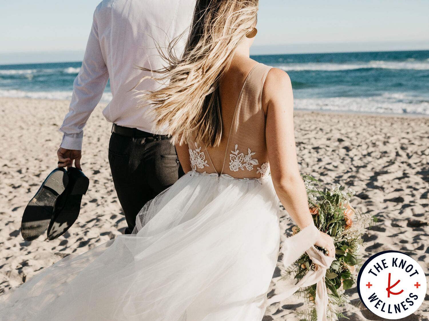 Bride and groom walking on beach on wedding day