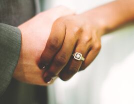 couple holding hands with engagement ring