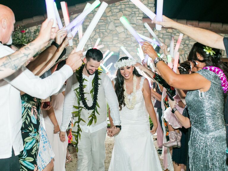 Bride and groom walk under foam glow sticks.
