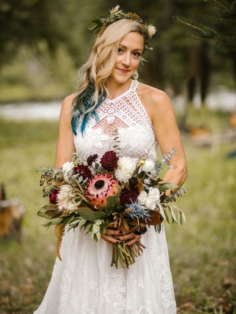Bride wears a flower crown in her hair and holds a bouquet of dahlias. 