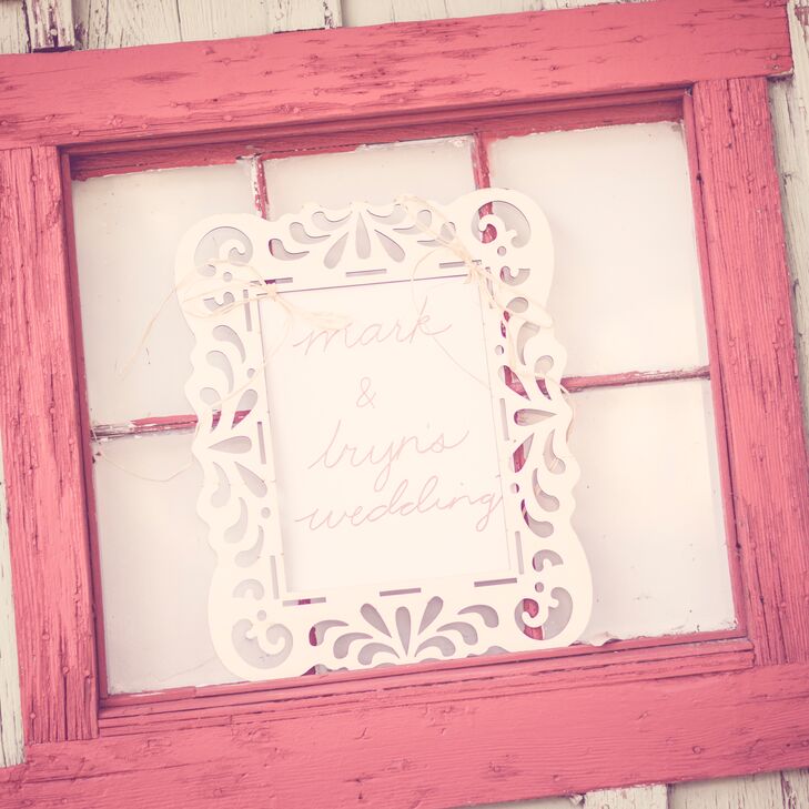 The bride and groom went for a neutral color palette to bring out the rustic feel of their outdoor wedding. The reception decor featured some coral accents, like this rustic window frame with a custom sign.