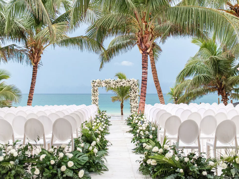 A beachside tropical wedding with a beautiful white floral archway.