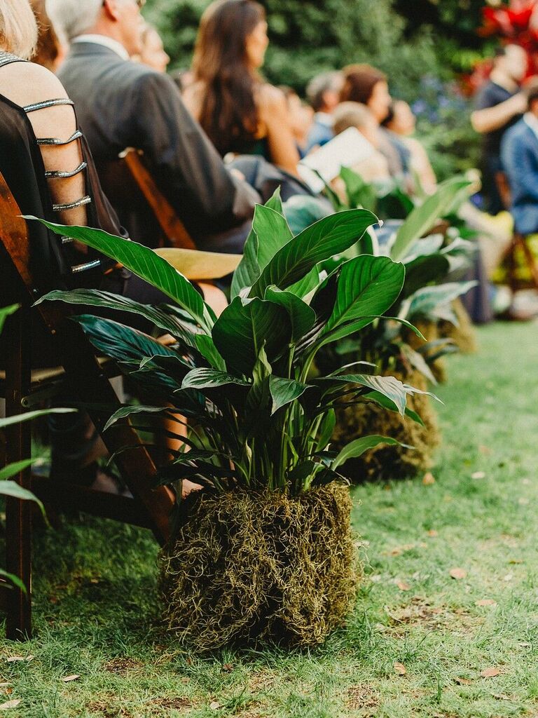 wedding ceremony aisle marker with tropical palm leaves displayed on top of moss base