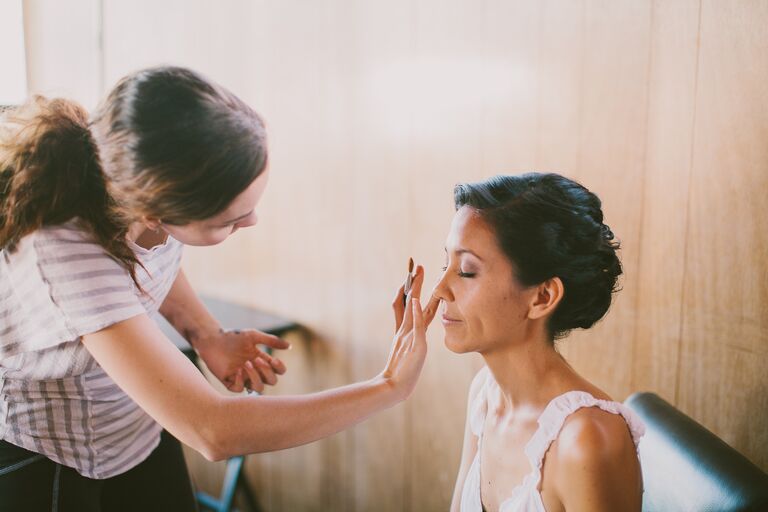 wedding makeup artist applying makeup to a bride on her wedding day