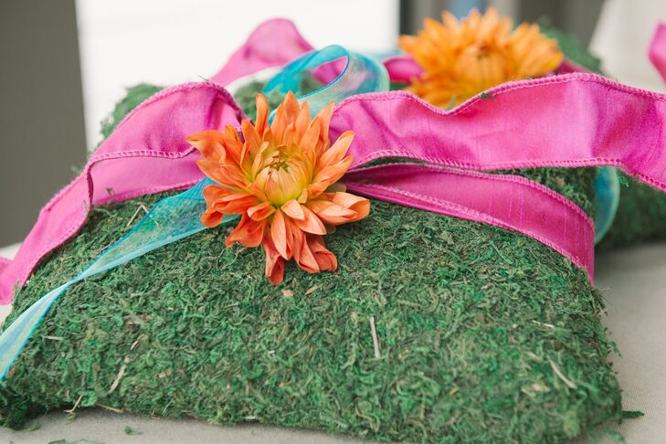 Bright orange dahlias and pink ribbon added a fresh punch of color to the mossy ring pillow.