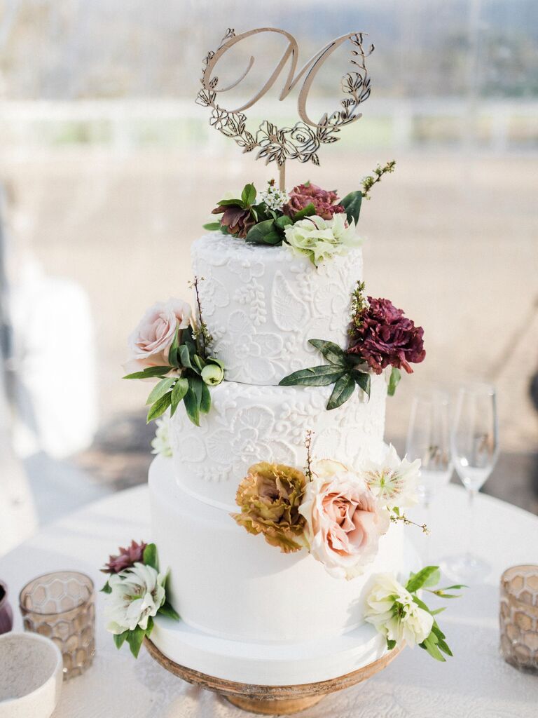 white fondant wedding cake with hand-piping decoration and fresh flowers