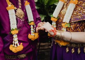 Bride and Groom in Traditional Khmer Clothing in Purple, Gold Holding Hands