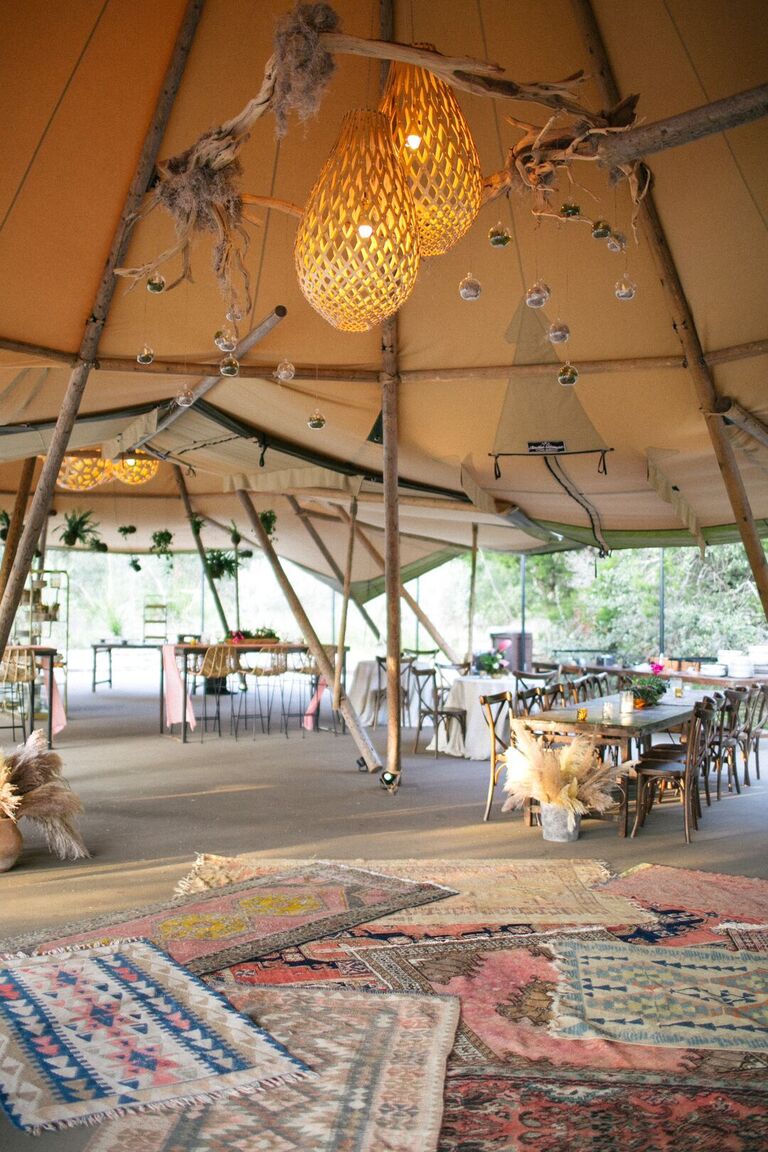 Tented reception with chandeliers and rugs for decoration
