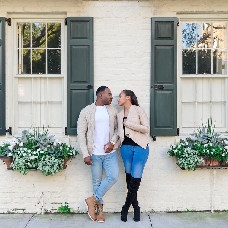 Couple holding hands and looking at each other in front of historic home in Charleston, South Carolina
