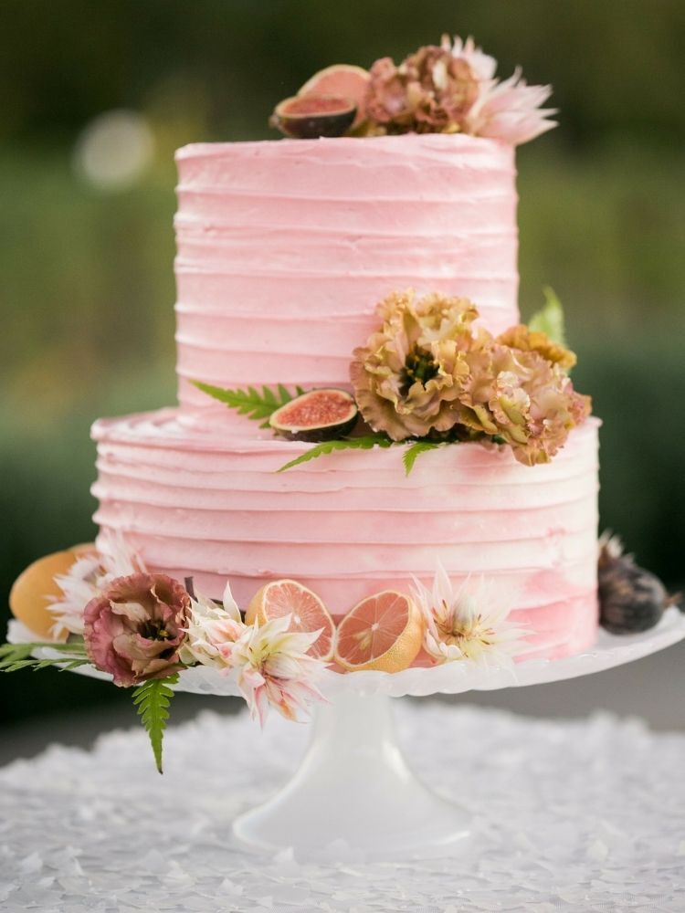 two-tier pink buttercream cake with fresh citrus