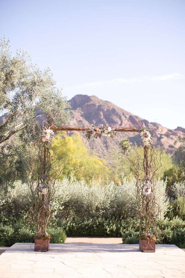 While the couple decided to keep the decor to a minimum, a few key details were added to the ceremony site for a polished finish. A curly willow wedding arch decorated with bunches of romantic blush and cream-colored roses stood on the stone patio at the head of the aisle and framed the couple as they exchanged vows.