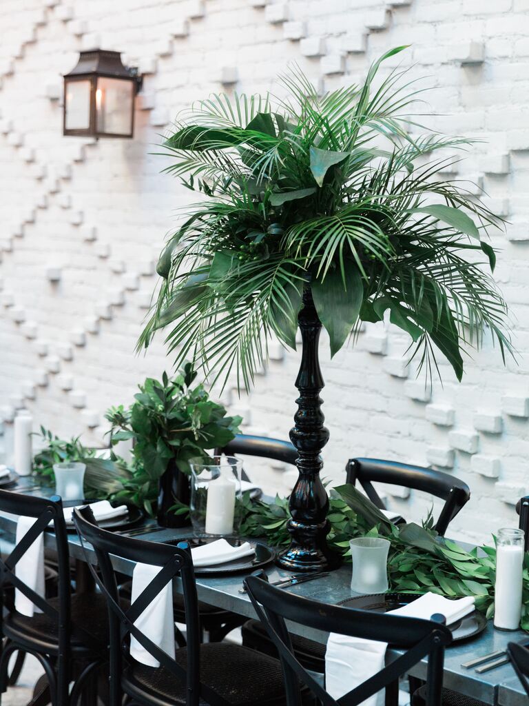 modern tropical tall wedding centerpiece with palm leaves and black wooden pedestal base