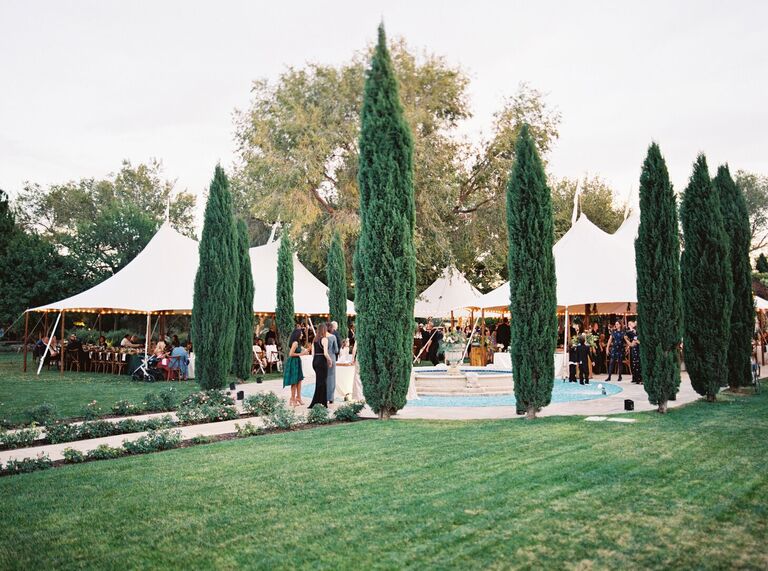 Outdoor tented cocktail hour with evergreen trees