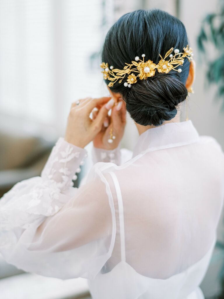 back of bride's head with low chignon wedding updo accented with gold and pearl flower comb