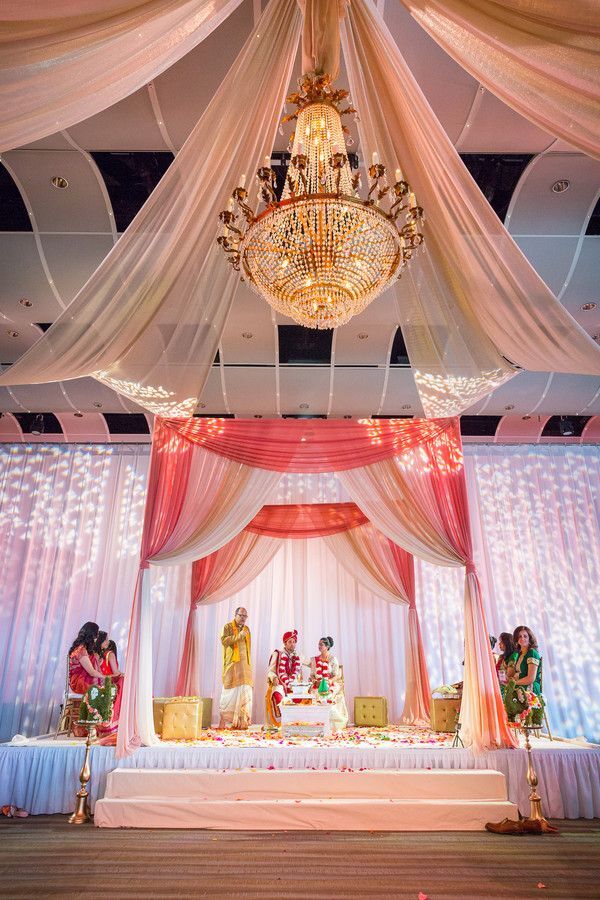 Mandap in hotel ballroom with crystal chandelier and fabric draping