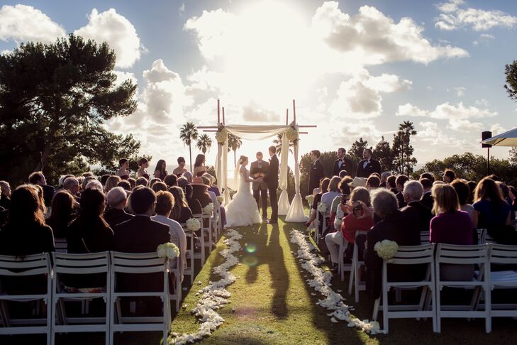 The aisle was lined in a zig zag of ivory rose petal with matching bouquets hung on chairs throughout. The tall arbor was made of criss-crossed bamboo and draped in a delicate sheer white fabric.